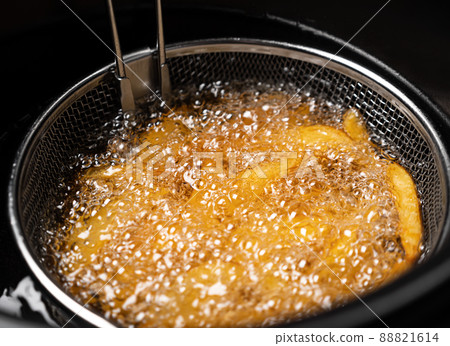 Cooking potatoes wedges in deep fryer 88821614