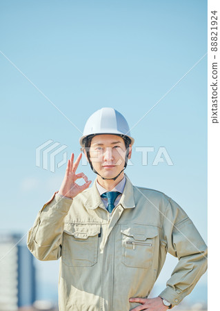一個穿著工作服的年輕人在藍天下擺出OK的姿勢 88821924