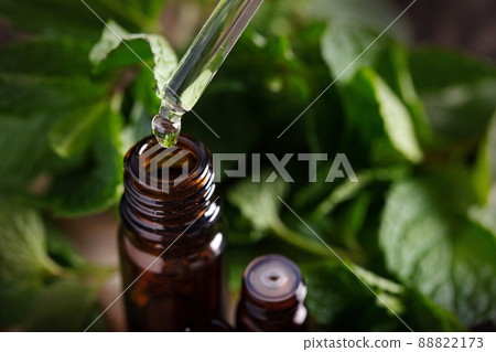 Essential oil falling from glass dropper into amber bottle 88822173