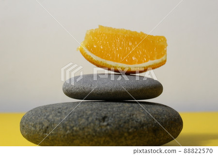 a ballans tower of grey stones and grapefruit orange fruit on a white yellow background with room for text. Benefits of Energy Health Importance Vitamin 88822570