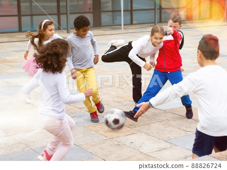 Happy tween girls and boys playing football in schoolyard 88826724