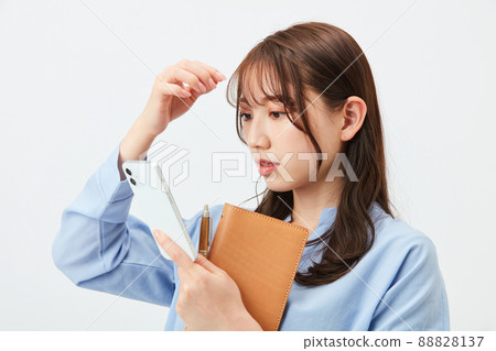 一位年輕的商務休閒女性,用智能手機相機調整髮型 一位年輕的商務休閒女性,用智能手機相機調整髮型 88828137