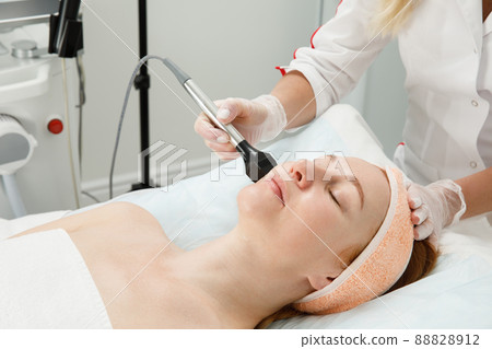 A woman receives laser treatment of the face in a cosmetology clinic, a concept of skin rejuvenation is being developed. laser peeling A woman receives laser treatment of the face in a cosmetology clinic, a concept of skin rejuvenation is being developed. laser peeling 88828912
