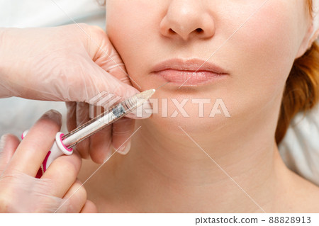 A woman makes lip shape correction in a cosmetology clinic. Lips injections, lip augmentation. A woman makes lip shape correction in a cosmetology clinic. Lips injections, lip augmentation. 88828913