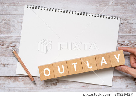 Blocks, notebooks, pens, hands with "OUTLAY" written on them Blocks, notebooks, pens, hands with "OUTLAY" written on them 88829427