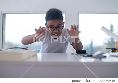 A boy in eyeglasses rolling small wheels on the table 88829646