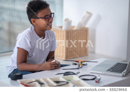 A dark-skinned boy constructing a transformer and looking busy A dark-skinned boy constructing a transformer and looking busy 88829668