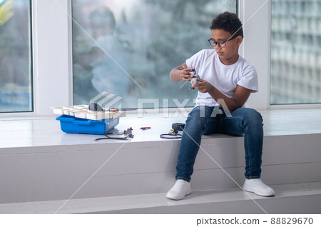 A dark-skinned boy constructing a transformer and looking busy A dark-skinned boy constructing a transformer and looking busy 88829670