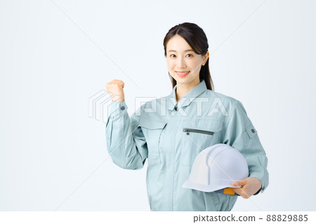 一名年輕的女工在做膽量姿勢時拿著頭盔 一名年輕的女工在做膽量姿勢時拿著頭盔 88829885