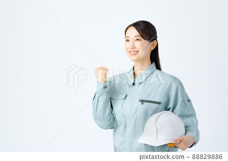 一名年輕的女工在做膽量姿勢時拿著頭盔 一名年輕的女工在做膽量姿勢時拿著頭盔 88829886