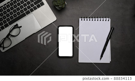 Black office desk with smart phone, laptop computer and notepad. Top view, flat lay. 88834113