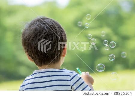 Back view of a boy looking at soap bubbles in the park 88835164