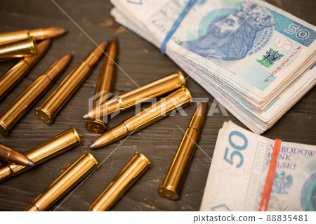 Scattered rifle cartridges lying next to a file of banknotes. Scattered rifle cartridges lying next to a file of banknotes. 88835481
