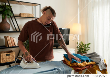 Young Man Ironing Clothes Young Man Ironing Clothes 88835978