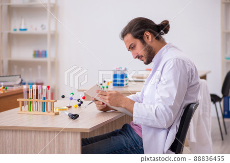 Young male chemist sitting at the desk in the classroom 88836455