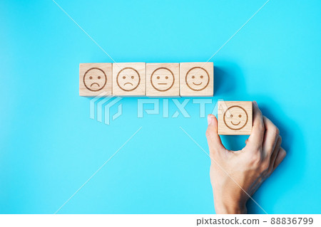 Man hand holding emotion face block. Customer choose Emoticon for user reviews. Service rating, ranking, customer review, satisfaction, evaluation and feedback concept 88836799