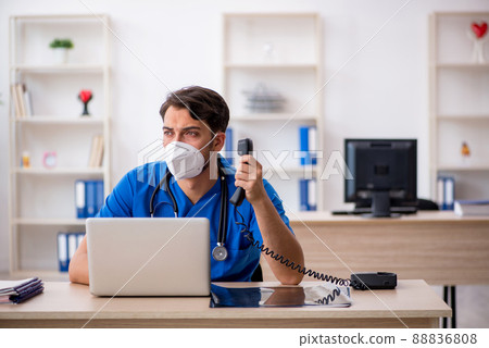 Young male doctor working in the clinic during pandemic 88836808