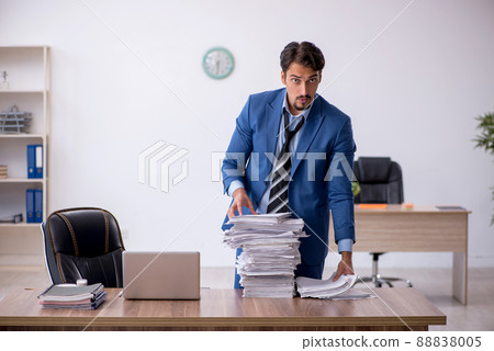 Young male employee unhappy with excessive work in the office Young male employee unhappy with excessive work in the office 88838005