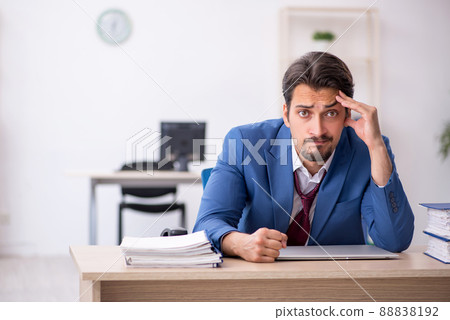 Young male employee unhappy with excessive work in the office Young male employee unhappy with excessive work in the office 88838192