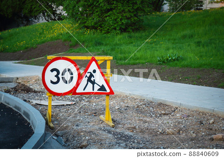 Construction road signs with number and digging man with shovel symbol on sandy road under construction 88840609