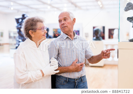 mature European couple examines paintings in an exhibition in hall of art museum 88841722