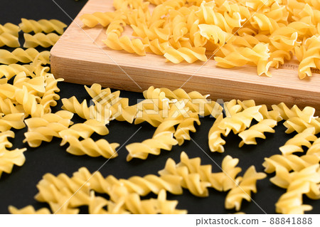 Uncooked Fusilli Pasta Scattered on Wooden Board Uncooked Fusilli Pasta Scattered on Wooden Board 88841888