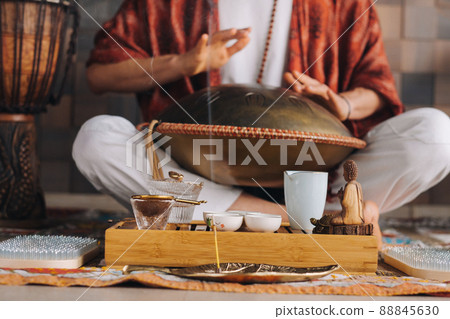 Close-up of a man's hand playing a modern musical instrument - the Orion tongue drum during the tea ceremony Close-up of a man's hand playing a modern musical instrument - the Orion tongue drum during the tea ceremony 88845630