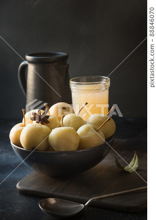 Pickled apples in bowl and apple sidr on dark stone table. 88846070