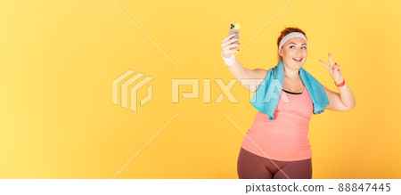 Smiling woman with oversized body makes selfie after workout 88847445