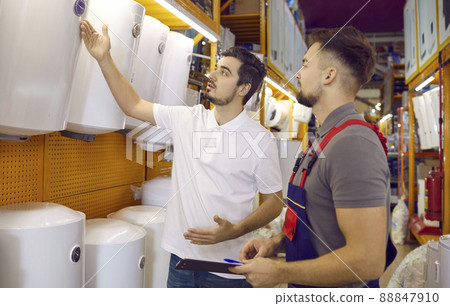Man on advice of seller chooses new heating water boiler in building materials store. 88847910
