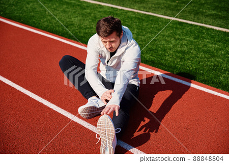 Man in sport clothers does a warm-up exercises at stadium track before jogging outdoors, Healthy lifestyle Man in sport clothers does a warm-up exercises at stadium track before jogging outdoors, Healthy lifestyle 88848804