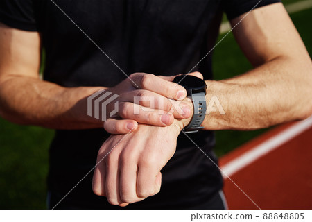 Man checking fitness watch after exercises at stadium rack Man checking fitness watch after exercises at stadium rack 88848805