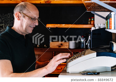 Waiter cashing up a service at the cash register. Waiter registering an order. 88849672