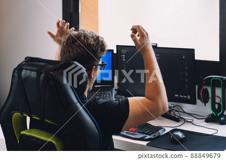 young blond man happily celebrating winning a video game on his computer. 88849679