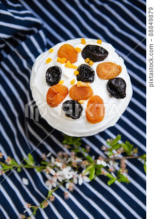 Easter cake, decorated with dried apricots and prunes, stands on a striped blue apron, a flowering branch. Easter religious holiday concept. Easter cake, decorated with dried apricots and prunes, stands on a striped blue apron, a flowering branch. Easter religious holiday concept. 88849879
