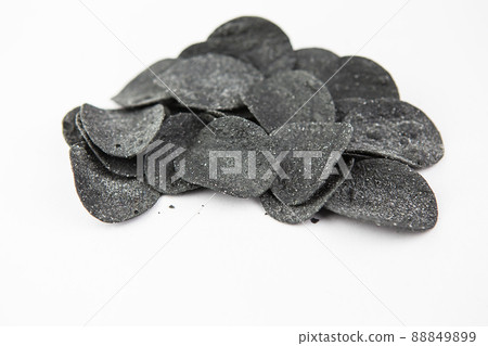 Selective focus. Macro chips. Spices and salt on black chips. Black chips with spices on a plate, cuttlefish ink food. Selective focus. Macro chips. Spices and salt on black chips. Black chips with spices on a plate, cuttlefish ink food. 88849899