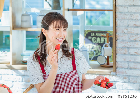 A woman picking and eating strawberries in the kitchen 88851230