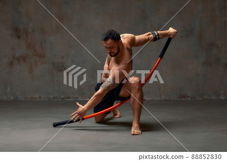 A ninja man holds on to a fighting stick and attacks close-up on gray studio background 88852830