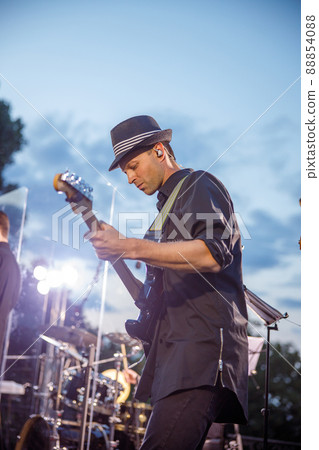 Male guitarist playing electric guitar under blue sky Male guitarist playing electric guitar under blue sky 88854088