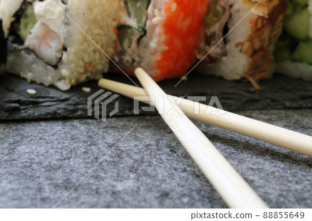 Rolls with shrimp, sesame, tuna, bacon, cheese, cucumber, vegetables and sushi sticks on a black board. Close-up. Japanese cuisine. Background. Rolls with shrimp, sesame, tuna, bacon, cheese, cucumber, vegetables and sushi sticks on a black board. Close-up. Japanese cuisine. Background. 88855649