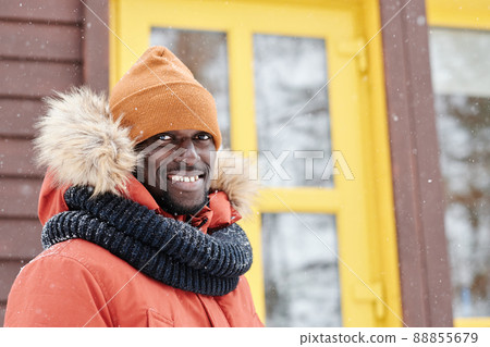 Young smiling black man in winter jacket, beanie hat and warm woolen scarf 88855679