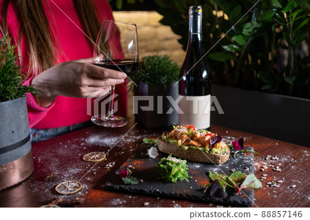 person eats fresh sandwich with avocado, red salmon fried fish, seaweed, wine 88857146