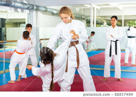 Teenager girls practicing karate in pairs Teenager girls practicing karate in pairs 88857499