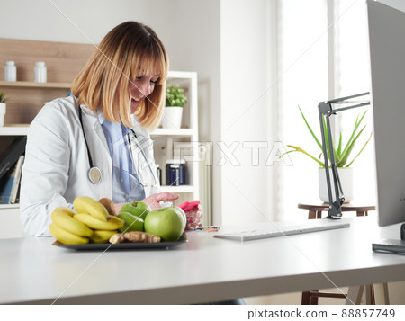 distracted female nutritionist chatting with smartphone in office studio 88857749