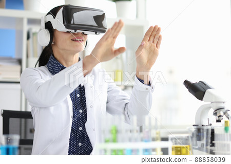 Young female doctor in virtual reality headset works on computer in hospital office 88858039