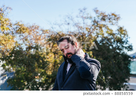 Young businessman massages his neck in the street Young businessman massages his neck in the street 88858559