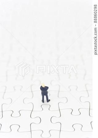 A businessman folding his arms on a jigsaw puzzle A businessman folding his arms on a jigsaw puzzle 88860298