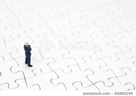 A businessman folding his arms on a jigsaw puzzle A businessman folding his arms on a jigsaw puzzle 88860299