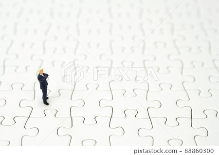 A businessman folding his arms on a jigsaw puzzle A businessman folding his arms on a jigsaw puzzle 88860300