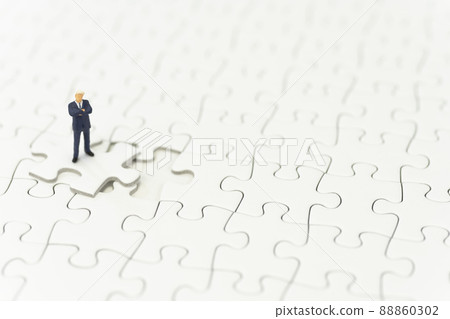 A businessman folding his arms on a jigsaw puzzle A businessman folding his arms on a jigsaw puzzle 88860302